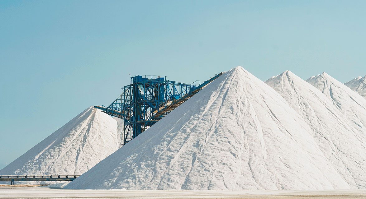 White mountains of salt for the early collection of road salt against a light blue sky